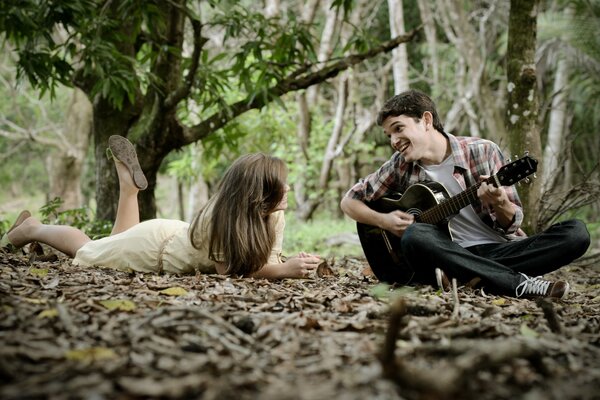 Chico tocando la guitarra chica en el bosque