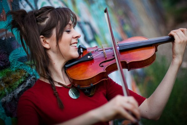 Lindsey Stirling gra na skrzypcach na tle ściany graffiti