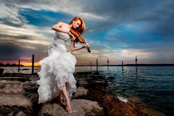 A girl in a white dress plays the violin