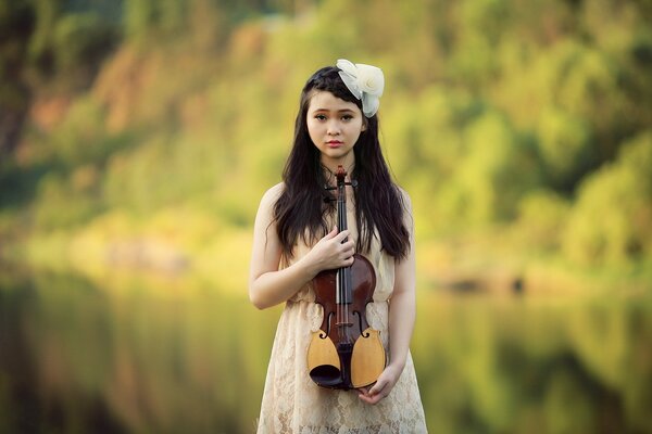 Chica con violín en la naturaleza en verano