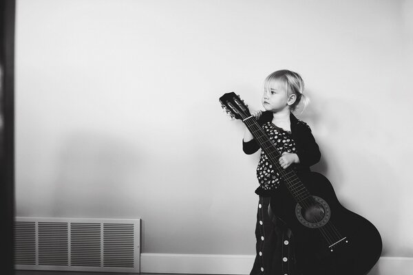 A little girl with a black guitar