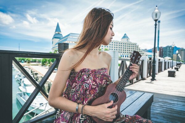 Guitar in the hands of a beautiful Asian woman