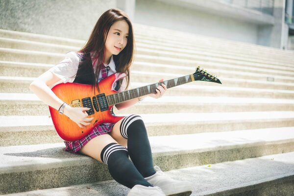 Studentessa in ginocchio con la chitarra in mano