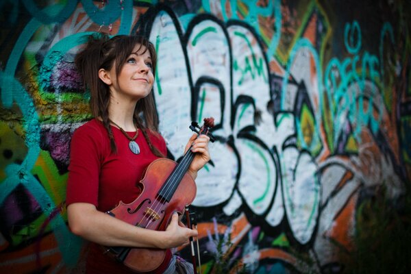 A beautiful woman with a violin on the background of a painted wall