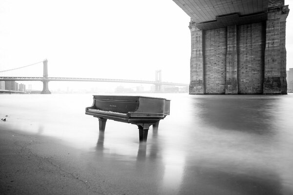 Klavier im Fluss auf dem Hintergrund der Brücke in schwarz und weiß