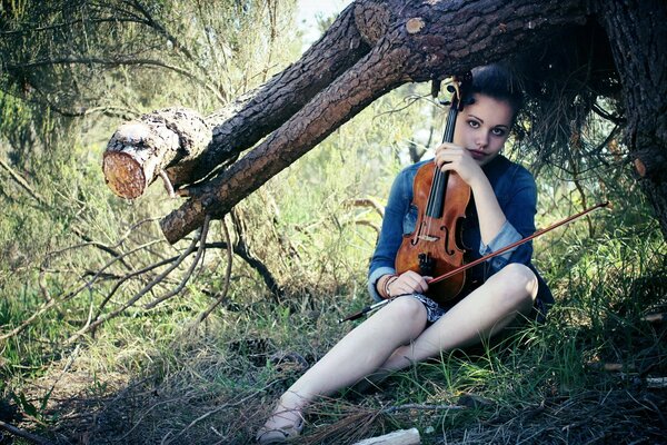 A girl in the forest with a violin and a bow