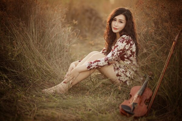 Una chica con un vestido de flores se sienta al lado del violín