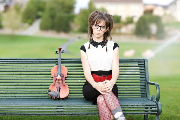 Una ragazza con un violino si siede su una panchina