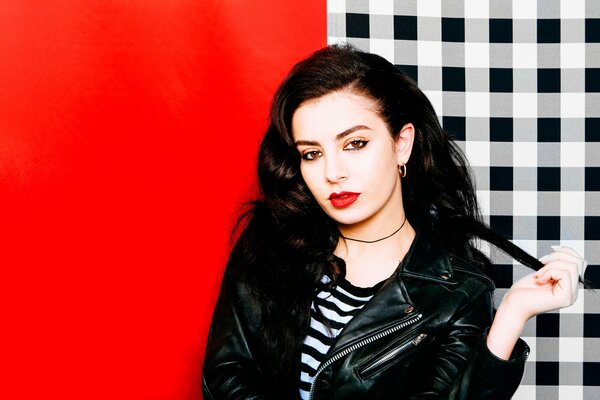 Cantante britannica Charli XCX su sfondo rosso e plaid con labbra rosse