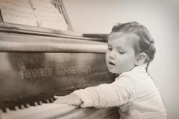 Mała dziewczynka naciska klawisze fortepianu