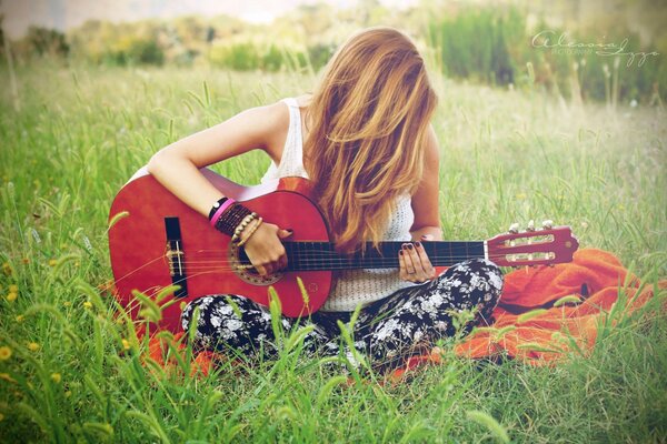 Mädchen spielt Gitarre auf dem Feld