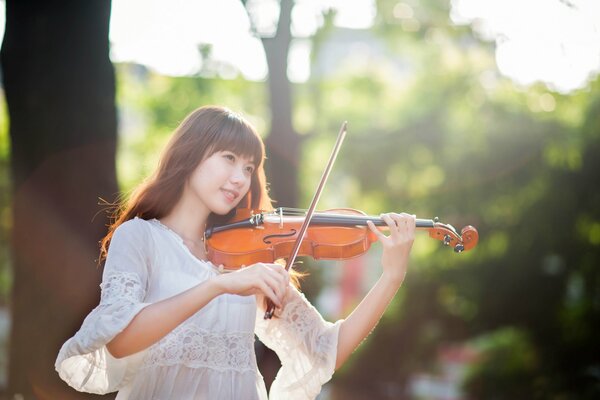 Oriental girl in a white dress plays the violin