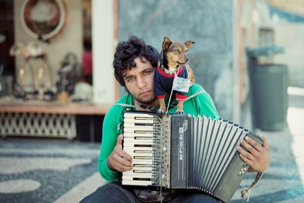 A street musician with a dog on his shoulder