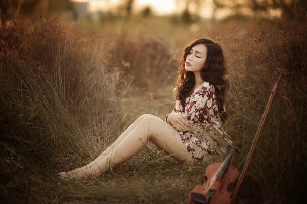 Asian girl with a violin in nature