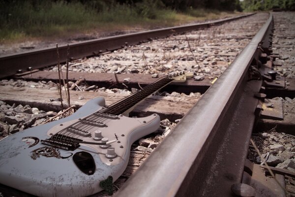 A musical guitar is lying on broken rails