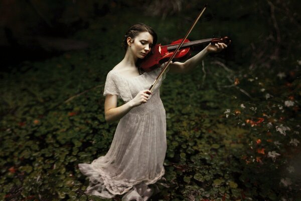 Chica en un vestido largo y blanco toca el violín