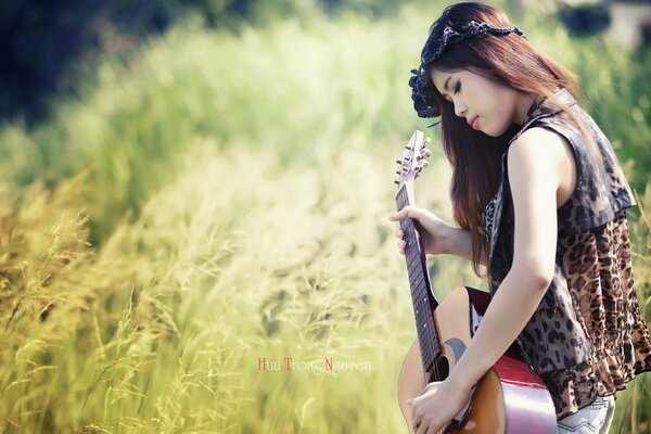 Chica en el campo tocando la guitarra