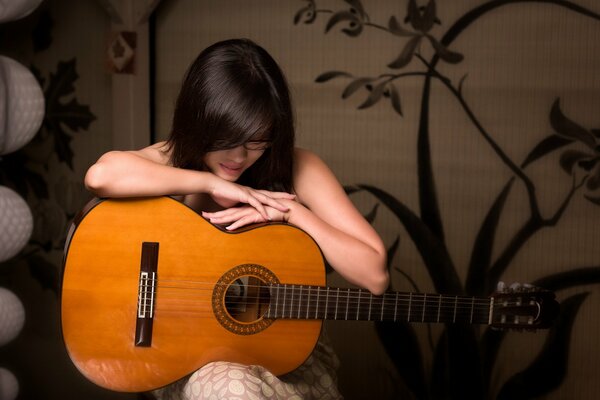 The girl sits and hugs the guitar