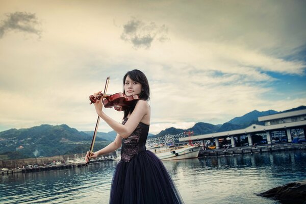 Violinista en un vestido de noche en la bahía