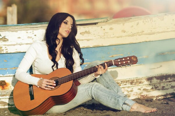 Mädchen mit Gitarre sitzt auf dem Sand