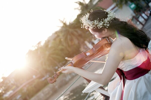 La chica de la corona de flores toca el violín