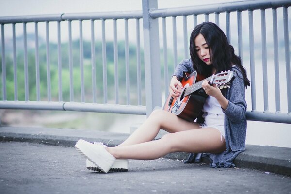 Hermosa chica tocando la música en la guitarra