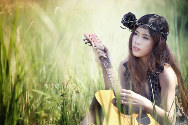 Asiatische Mädchen mit Gitarre im Feld