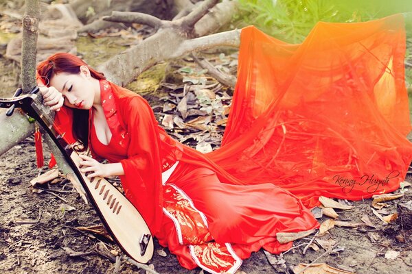 Girl in red with a zither in the forest