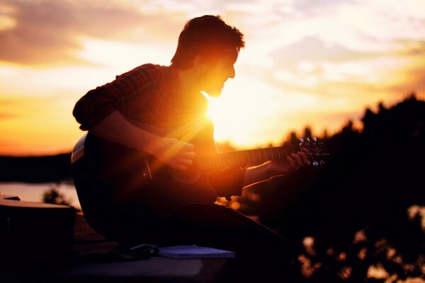 Chico tocando la guitarra al atardecer