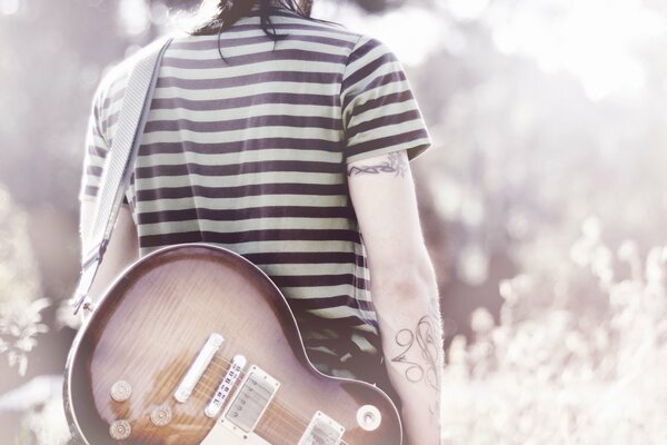 Musicista con chitarra con tatuaggi sulle mani