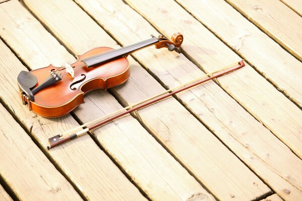 El violín y el arco se encuentran en el piso de madera