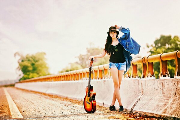 Chica en el camino con una guitarra