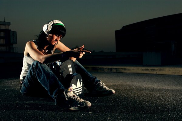 A girl with headphones and a bag is sitting on the roof