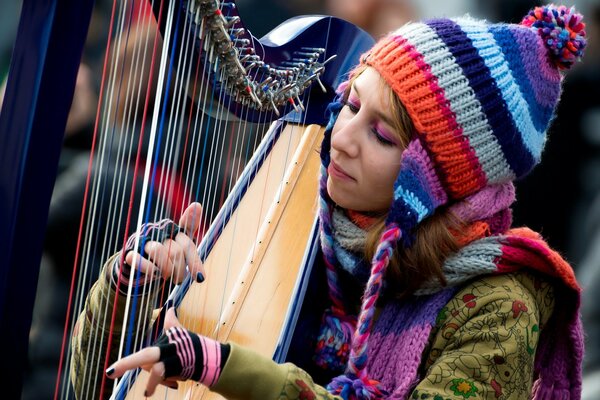 Mädchen spielt auf einer Harfe mit einer bunten Mütze