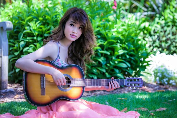 Brunette joue de la guitare dans le jardin