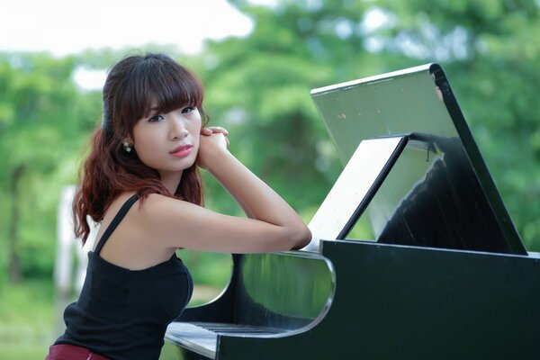 Chica asiática se sienta en el piano