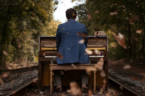 En el fondo del paisaje de otoño, un chico toca el piano