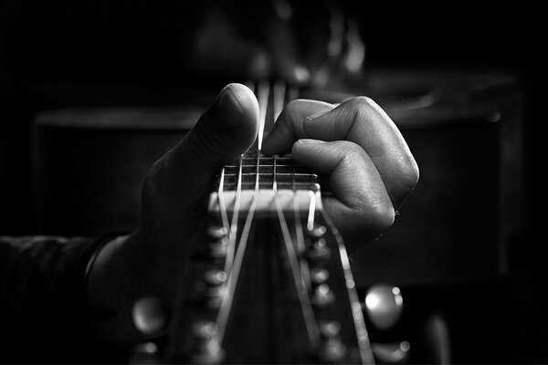 Les doigts de la main serrent les cordes de la guitare