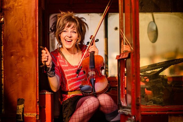 Lindsey Stirling con un violino in un autobus rosso