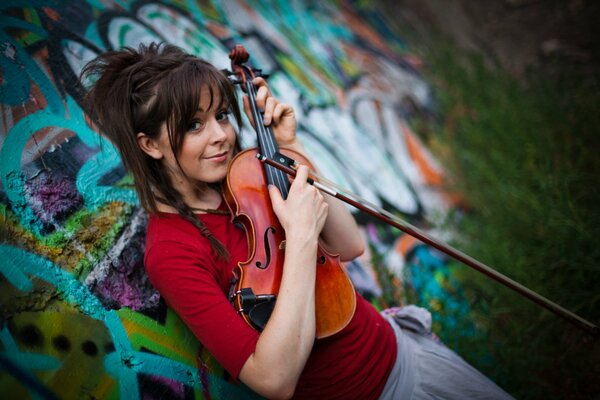 Hermosa chica con una chaqueta roja sostiene un violín en sus manos