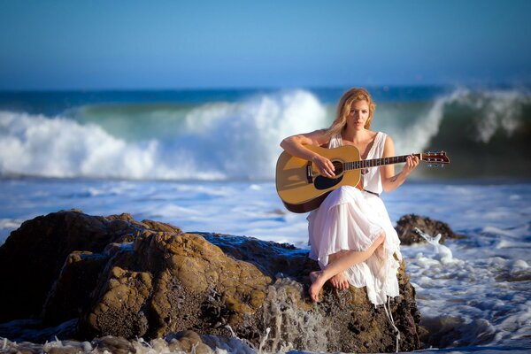 Chica sentada en la orilla del surf con una guitarra