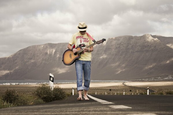 Der Typ mit der Gitarre geht die Straße entlang