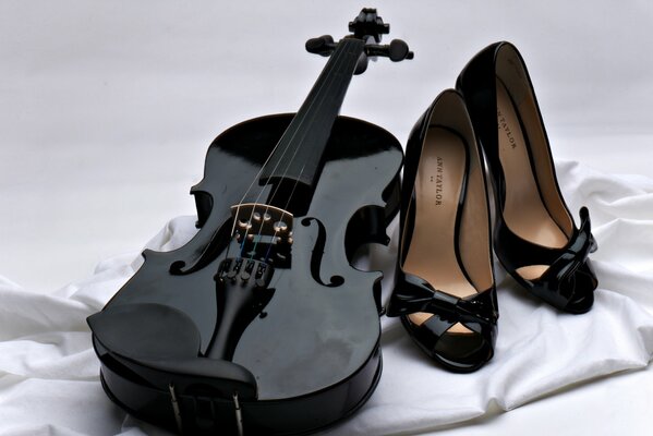 Violon noir et chaussures noires sur tissu blanc