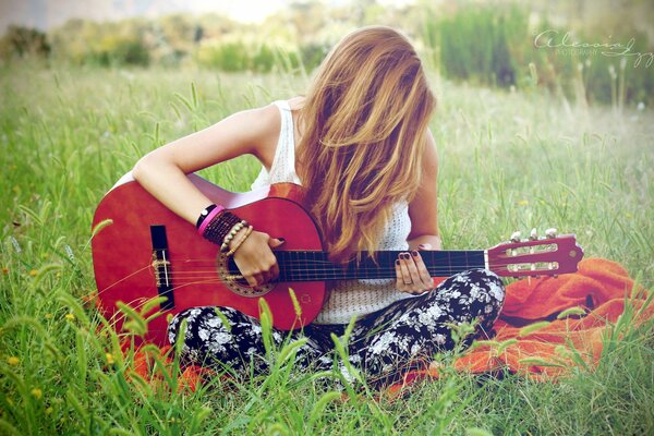 La ragazza con la chitarra si siede sull erba