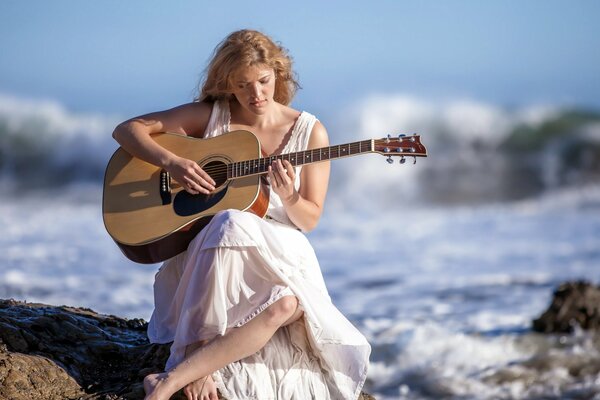 FILLE JOUANT N GUITARE PRÈS DE LA MER