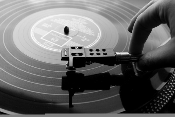 A man s hand chooses a song on a vinyl record