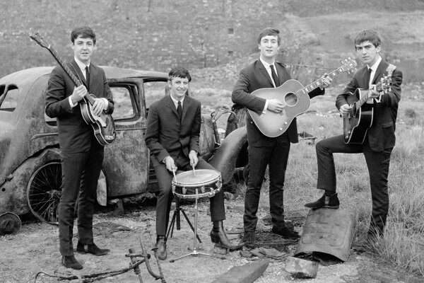 Schwarz-Weiß-Foto der Beatles-Gruppe am rostigen Auto