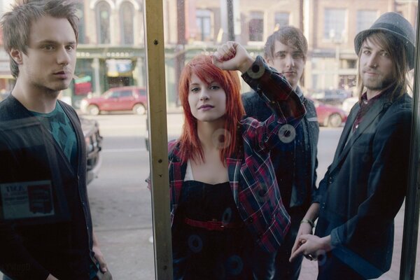 Fille et trois gars debout à la vitrine