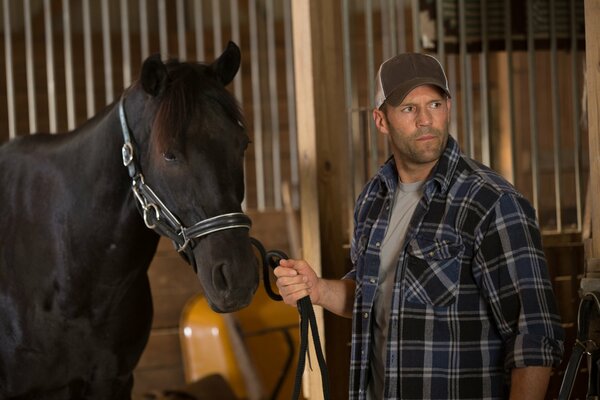 Jason Statham with a horse in the stable