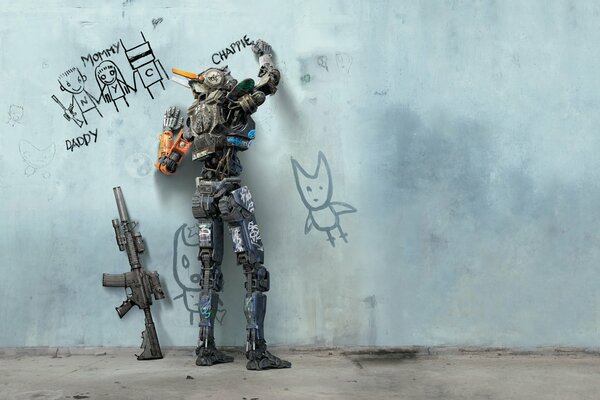 Der Roboter schreibt ein Wort an die Wand und eine Waffe steht in der Nähe